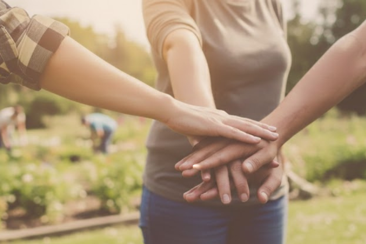 People with their hands stacked together, symbolizing community support in the workplace